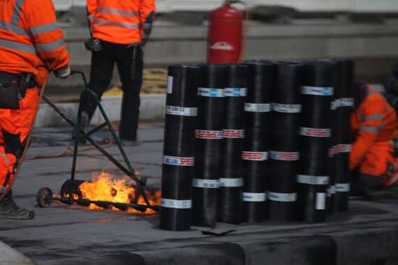 Ein Bauarbeiter bei der Arbeit, umgeben von Baustellenmaterialien und Maschinen.