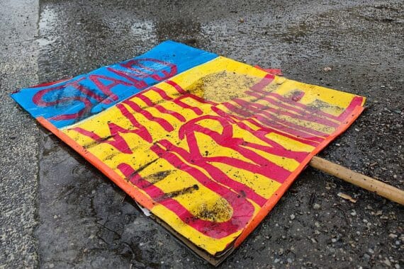 Schild "Stand with Ukraine" auf dem Boden symbolisiert den anhaltenden Konflikt und Pessimismus.