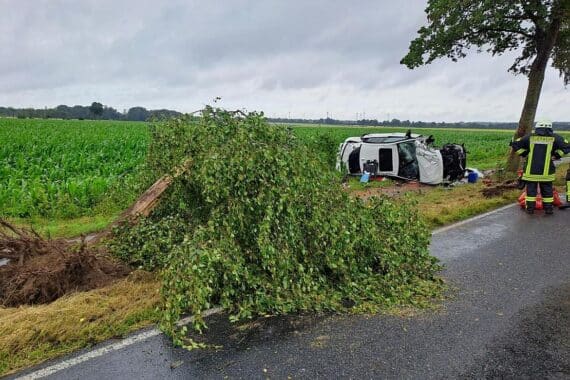 Ein schwer beschädigter BMW liegt auf der Seite, umgeben von Einsatzfahrzeugen und Rettungskräften.