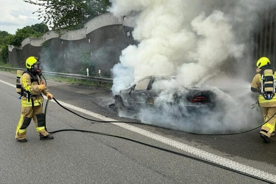 Brennender Pkw mit starker Rauchsäule, Feuerwehr im Einsatz, Verkehrsbehinderung auf Autobahnzubringer.
