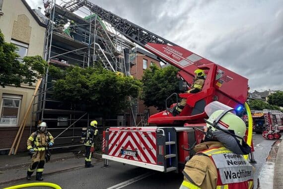 Feuerwehr löscht Dachstuhlbrand in Neuss, Rauchentwicklung und Einsatzkräfte sichtbar.