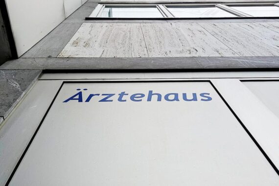 Ein modernes Ärztehaus mit Ärzten im Gespräch über Gesundheitsreformen und Patientenversorgung.