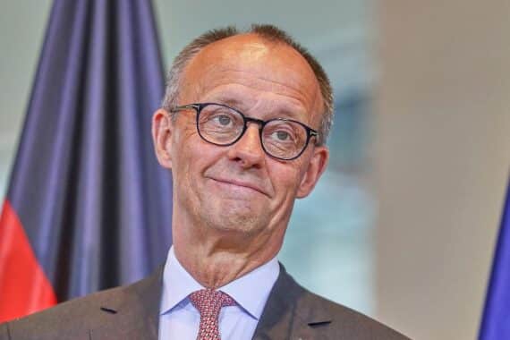 Friedrich Merz, CDU, bei einer Rede, umgeben von politischen Plakaten und Wählern.
