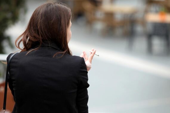 Raucherin in urbaner Umgebung, Symbol für aktuelle Debatte über Tabaksteuer und Rauchverbote.