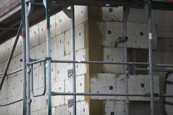 Gerüstbau mit Wärmedämmung, modernes Gebäude, effiziente Sanierung, Förderung der Energiewende in Hessen.