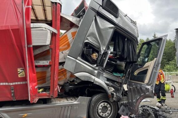 Auffahrunfall auf Autobahn: beschädigter Lkw, verschobene Ladung und Polizei vor Ort.
