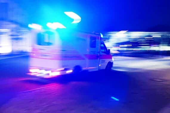 Rettungswagen und Unfallstelle mit Motorrädern und Linienbus, symbolisieren tragisches Unglück.