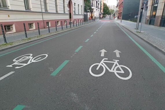 Fahrradstraße mit nachhaltigen Mobilitätsprojekten und emissionsfreien Fahrzeugen in einer urbanen Umgebung.