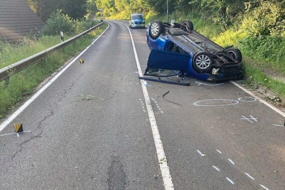 Auto überschlägt sich auf Venwegener Straße, Passanten leisten Erste Hilfe, Polizei sichert Unfallort.