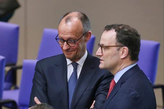 Friedrich Merz und Jens Spahn lächeln freundlich, symbolisieren Zusammenarbeit und politische Zuversicht.