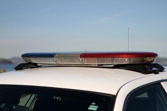 US-Polizeiauto vor einer Szenerie, die Ermittlungen nach Schüssen auf Politiker darstellt.