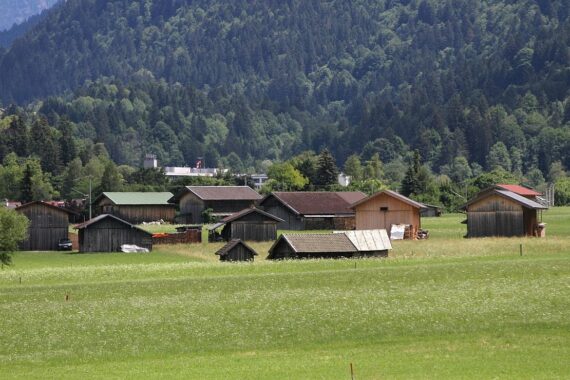 Sonnenuntergang über Schloss Elmau, umgeben von Bergen; warme Temperaturen und Gewitterwarnung.