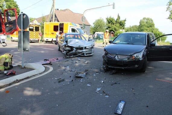 Verkehrsunfall mit zwei verletzten Personen an Kreuzung, Polizei und beschädigte Fahrzeuge sichtbar.