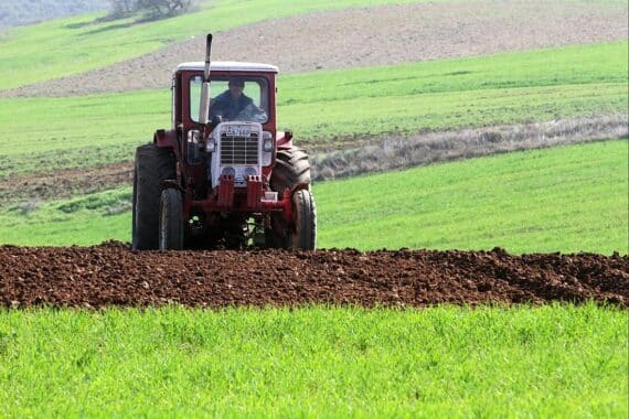 Bauer mit Traktor symbolisiert Herausforderungen der Landwirtschaft und Mindestlohnfragen für Saisonarbeitskräfte.