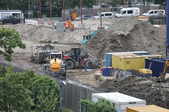 Bauarbeiter an einer Baustelle, inaktiv mit Baugeräten, symbolisiert langsame Mittelvergabe für Projekte.