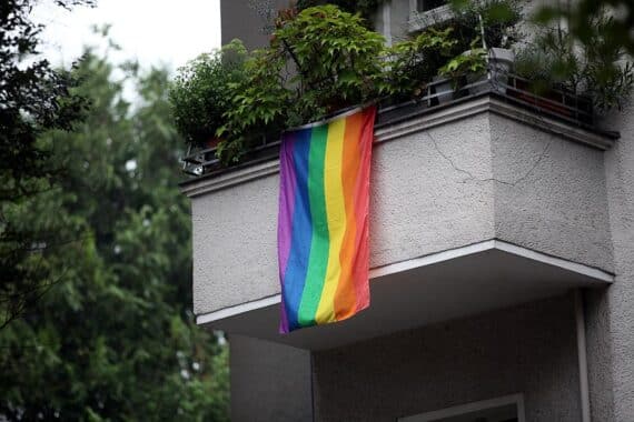 Regenbogenflagge vor urbanem Hintergrund, symbolisiert Vielfalt und den Kampf gegen Queerfeindlichkeit in Berlin.