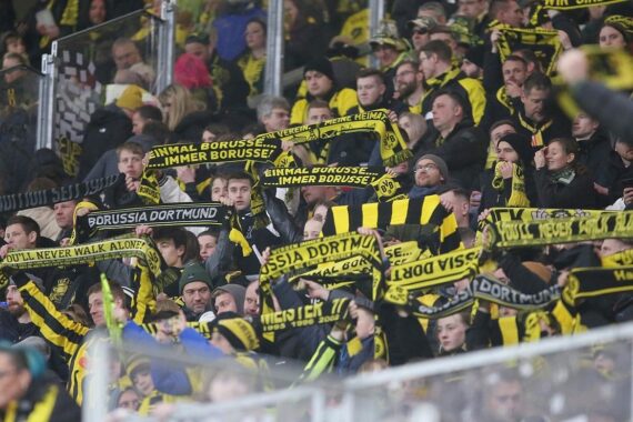 BVB-Fans jubeln im Stadion, darunter ein Banner für das Freundschaftsspiel gegen OSC Lille.