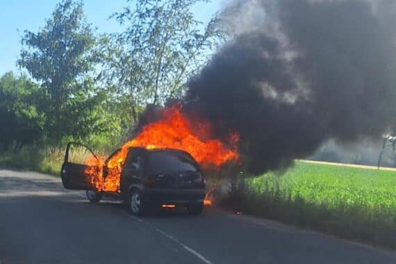 Feuerwehrleute öffnen Motorhaube eines brennenden PKW mit Halligan-Tool zur Brandbekämpfung.