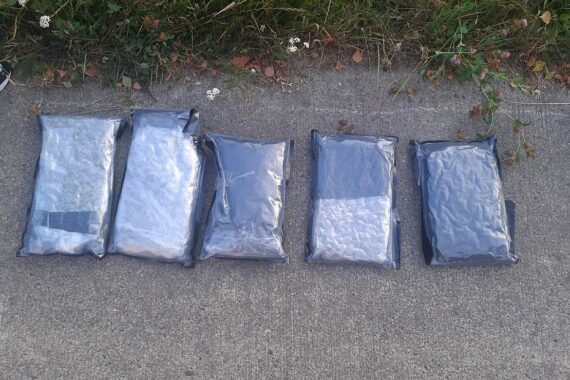 Zwei Polizisten überprüfen Fahrzeug, während Marihuana in Beuteln sichtbar ist.