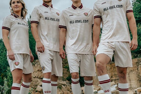 Vierte Spieler zeigen stolz das altweiße Auswärtstrikot im Sandsteinbruch, inspiriert von Dresdens Architektur.