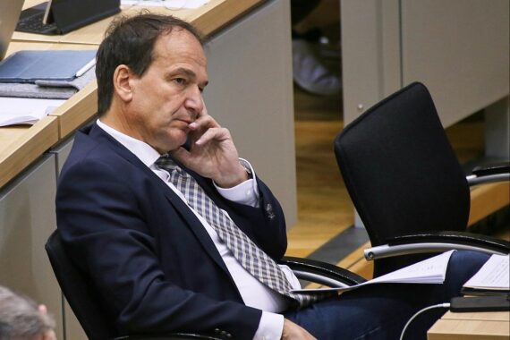 Skizzierung von Industrieanlagen, Schließungsandrohung, protestierende Arbeiter, politische Debatte, Dringlichkeit der Maßnahmen.