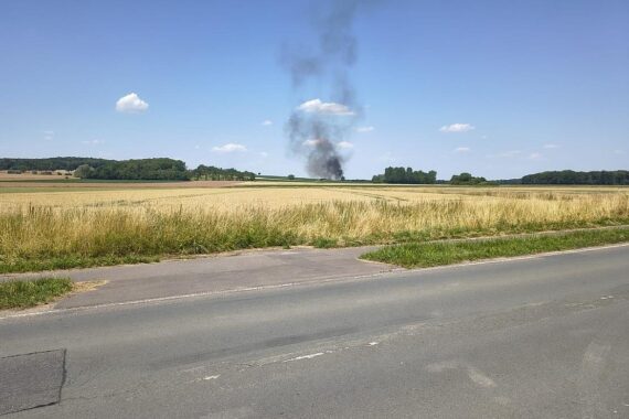 Rauchwolken über einem Feld, Feuerwehr im Einsatz, brennende Rundballenpresse, dramatische Szenen.