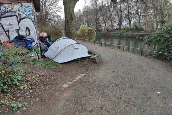 Obdachlose Menschen vor einer Unterkunft, die über geplante Hilfe für Wohnungslose informiert.