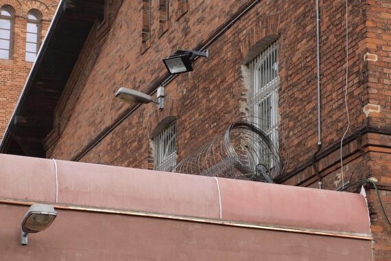 Ein modernes Gefängnisgebäude mit Baustellenschildern, symbolisiert den geplanten Neubau in Halle.