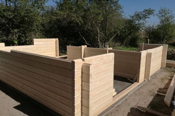 Unfertige Holzhütte als Symbol für nachhaltigen Wohnungsbau und neue Richtlinien in Sachsen.