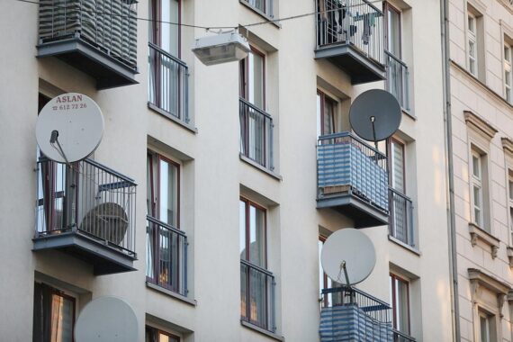 Satellitenschüssel an Wohnhaus symbolisiert moderne Technologien für nachhaltiges Bauen und regionale Entwicklung.