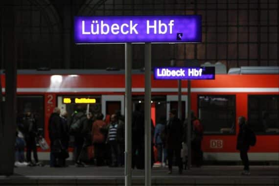 Passagiere am Lübecker Hauptbahnhof, besorgt über Bahnverkehr und Zukunft der Region.
