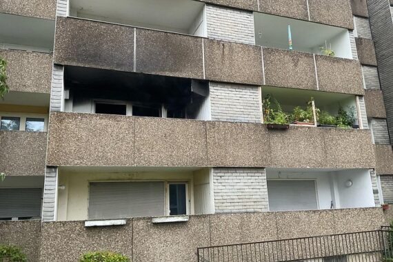 Feuerwehr im Einsatz: Wohnung brennt, Bewohner auf Balkon gerettet, Straßenblockade durch Einsatzkräfte.