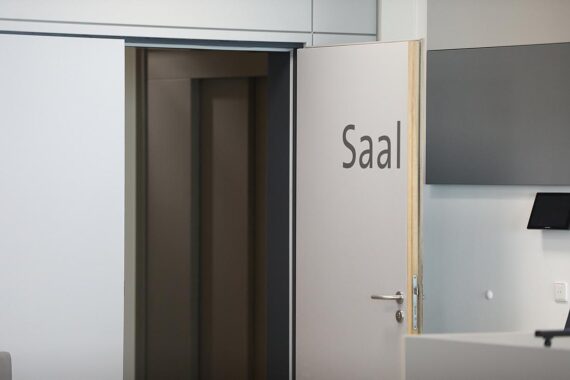 Verhandlungssaal mit Gerichtstischen, Richtersitz und Anklagebank, symbolisiert Rechtsprechung gegen Schwarzarbeit.