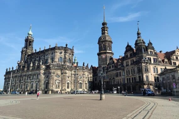 Sonniger Theaterplatz in Dresden, Menschen genießen warmes Wetter, klare Himmel, keine Regenwolken.