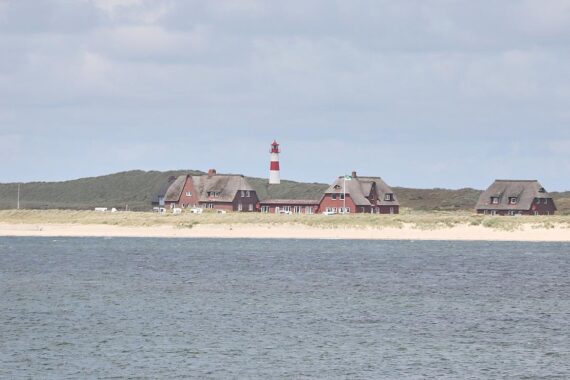 Leuchtturm an der Küste, sonniger Himmel und ruhiges Wetter mit milden Temperaturen.