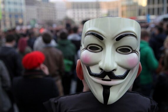 Guy-Fawkes-Maske symbolisiert Cyberkriminalität und Anonymous-Gruppe im Kontext eines schweren Cyberangriffs.