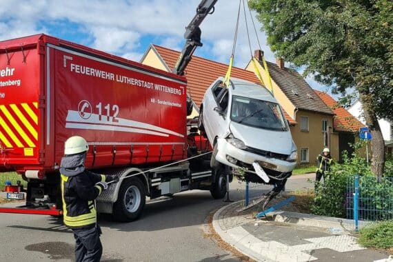 Verunfalltes Auto im Bach, Feuerwehr bei Bergung, beschädigtes Brückengeländer im Hintergrund.