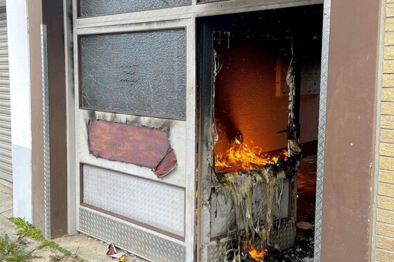 Brand im Mehrfamilienhaus: beschädigte Eingangszone mit Müllsäcken und Couch, Feuerwehr im Einsatz.