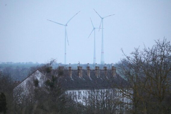 Ein Mehrfamilienhaus mit neuen Windrädern im Hintergrund für nachhaltige Energie in Braunschweig.