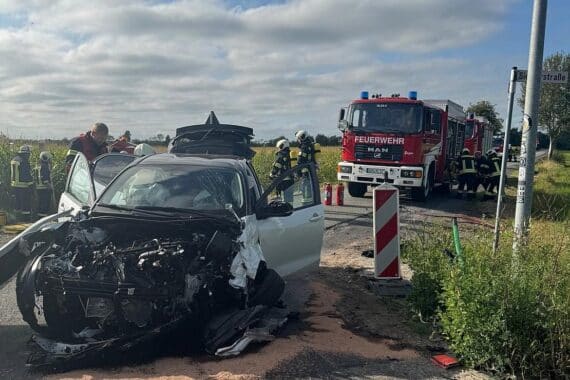 Unfallstelle mit verletzten Personen, Feuerwehr im Einsatz, Fahrzeug und Tanks, Sicherheitsmaßnahmen.