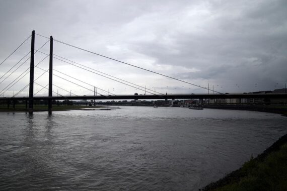 Rheinkniebrücke in Düsseldorf mit Verbotsschildern für Baden im Rhein und starken Wellen.