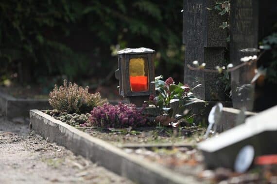 Friedhof mit Verbotsschildern für Kerzen und Lichter aufgrund Brandgefahr durch Trockenheit.