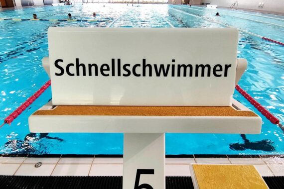 Schwimmbad mit Kindern beim Schwimmen, Symbol für Förderung und Sicherheit im Schwimmunterricht.