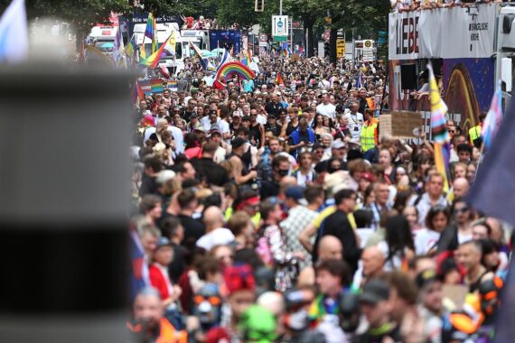 Bunte Parade mit Menschen, die für Vielfalt, Solidarität und den Schutz queerer Menschen demonstrieren.
