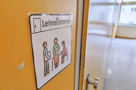 Genderzeichen vor einem Lehrerzimmer, symbolisiert Vielfalt und Inklusion in der Schulbildung.