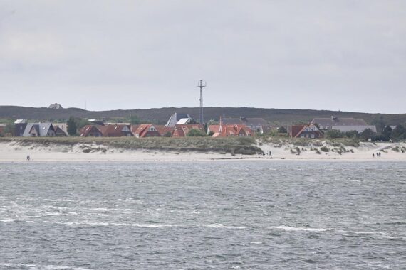 Strandansicht auf Sylt mit Fokus auf das moderne Jugendgästehaus und jugendliche Aktivitäten.