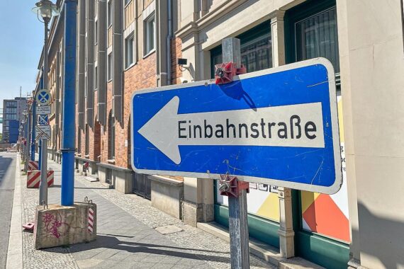 Ein beschilderter Straßenabschnitt mit Einbahnstraßen-Signal und Baustellensicherung.
