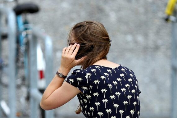 Junge Frau hält Handy, Symbol für Betrugswarnung und digitale Sicherheit.