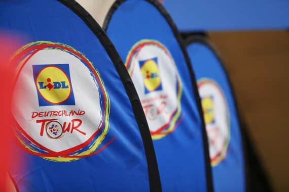 Polizeipräsenz und Radfahrer in urbaner Umgebung der Deutschlandtour 2025. Sicherheitsmaßnahmen sichtbar.