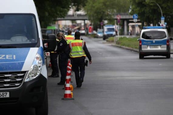 Polizeikontrolle mit mehreren Beamten an gewerblichen Fahrzeugen im Straßenverkehr fokussiert.